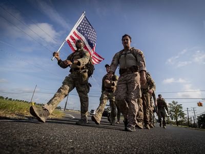 A service member carries a flag and leads his comrades at Joint Base McGuire-Dix-Lakehurst as they march in remembrance of 9/11 victims. More than 40 veterans died in the attacks.

