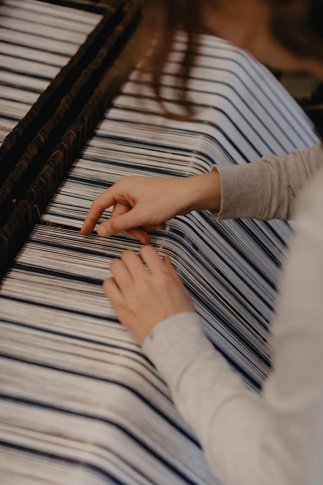 a close up of hands working on a textile machine