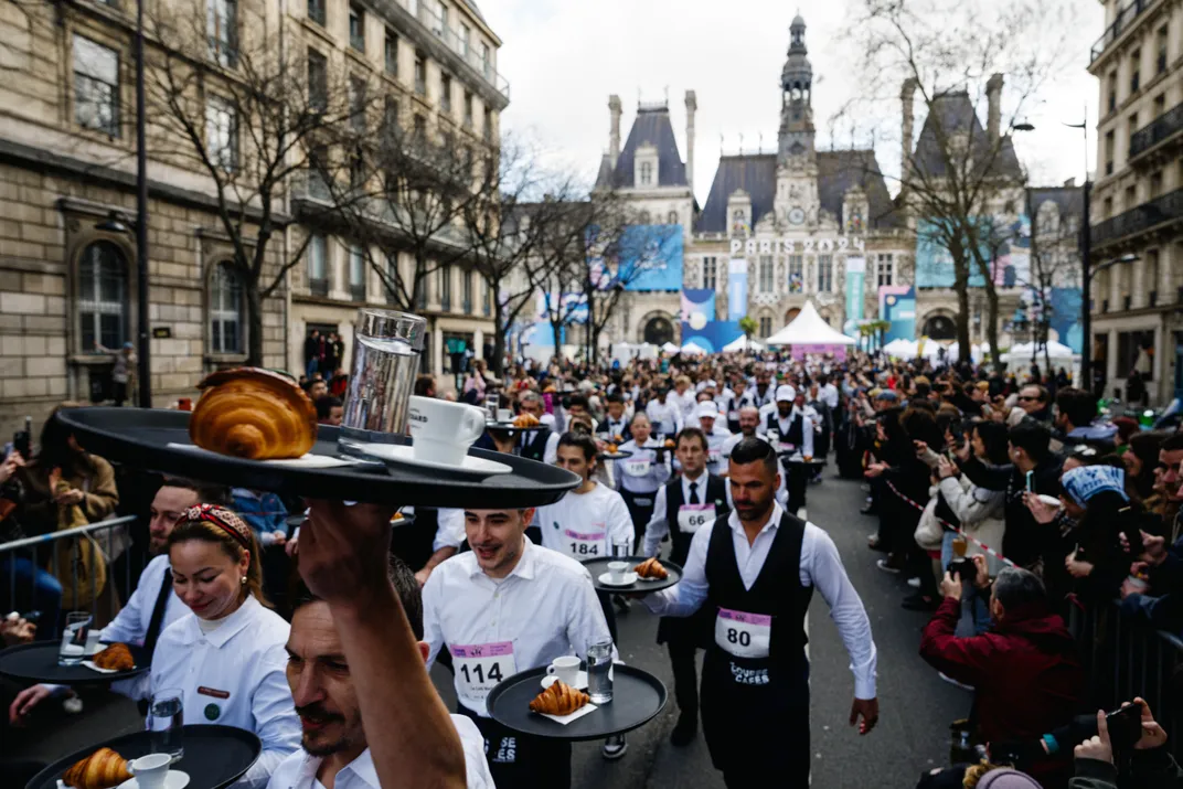 Waiters holding trays and walking through the street