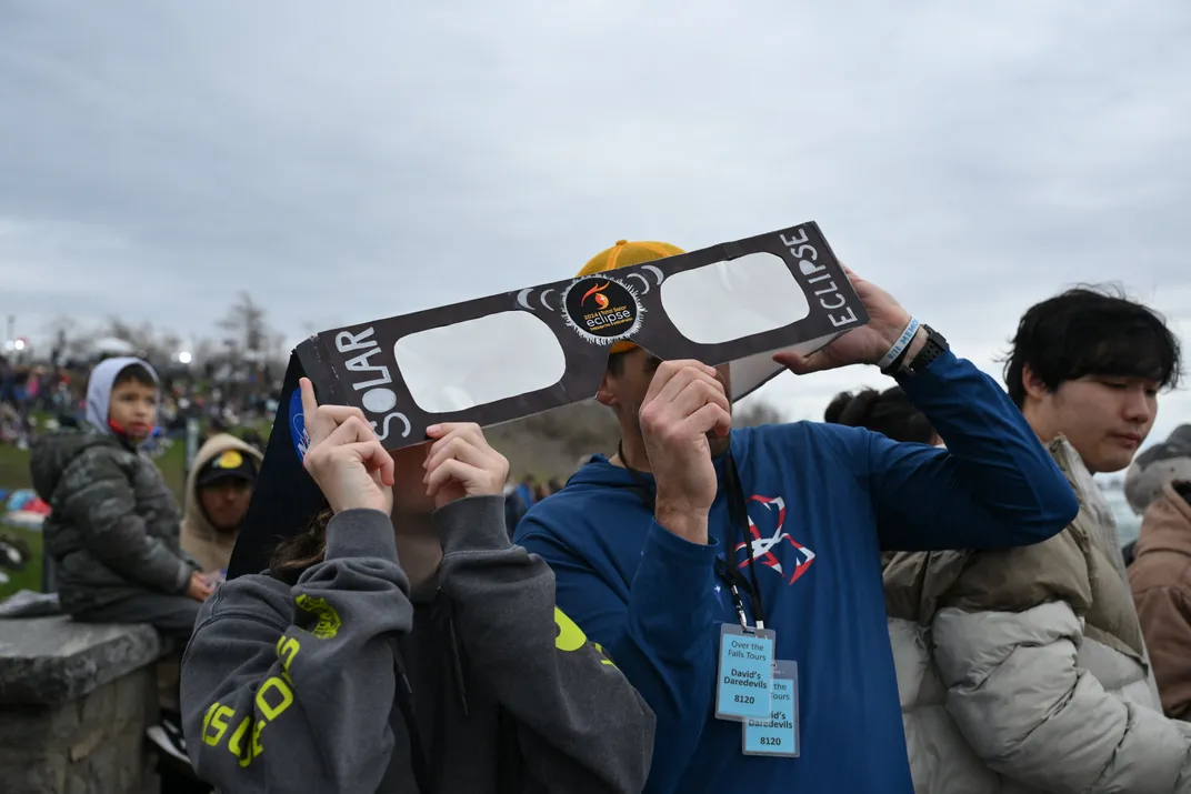 People watching the eclipse through giant glasses