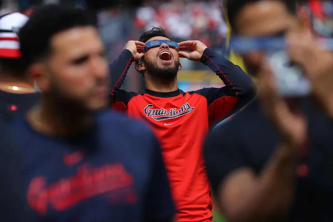 baseball player looking up at eclipse